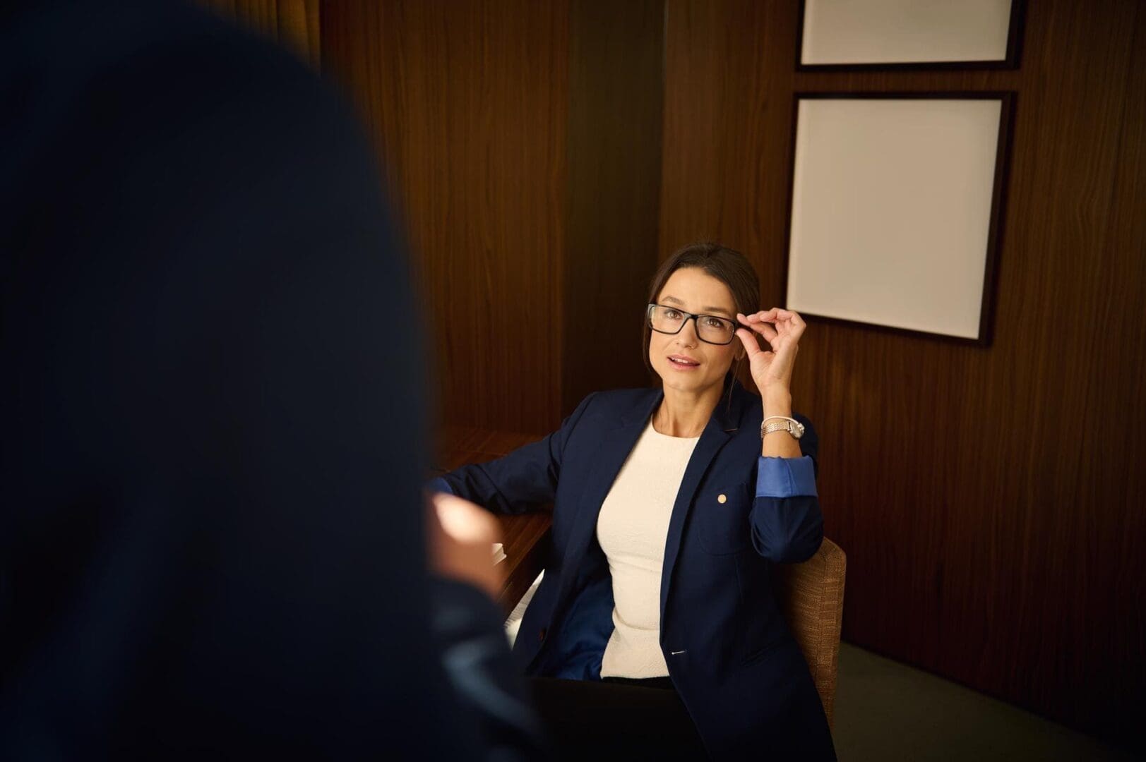 Woman adjusting glasses during a conversation.
