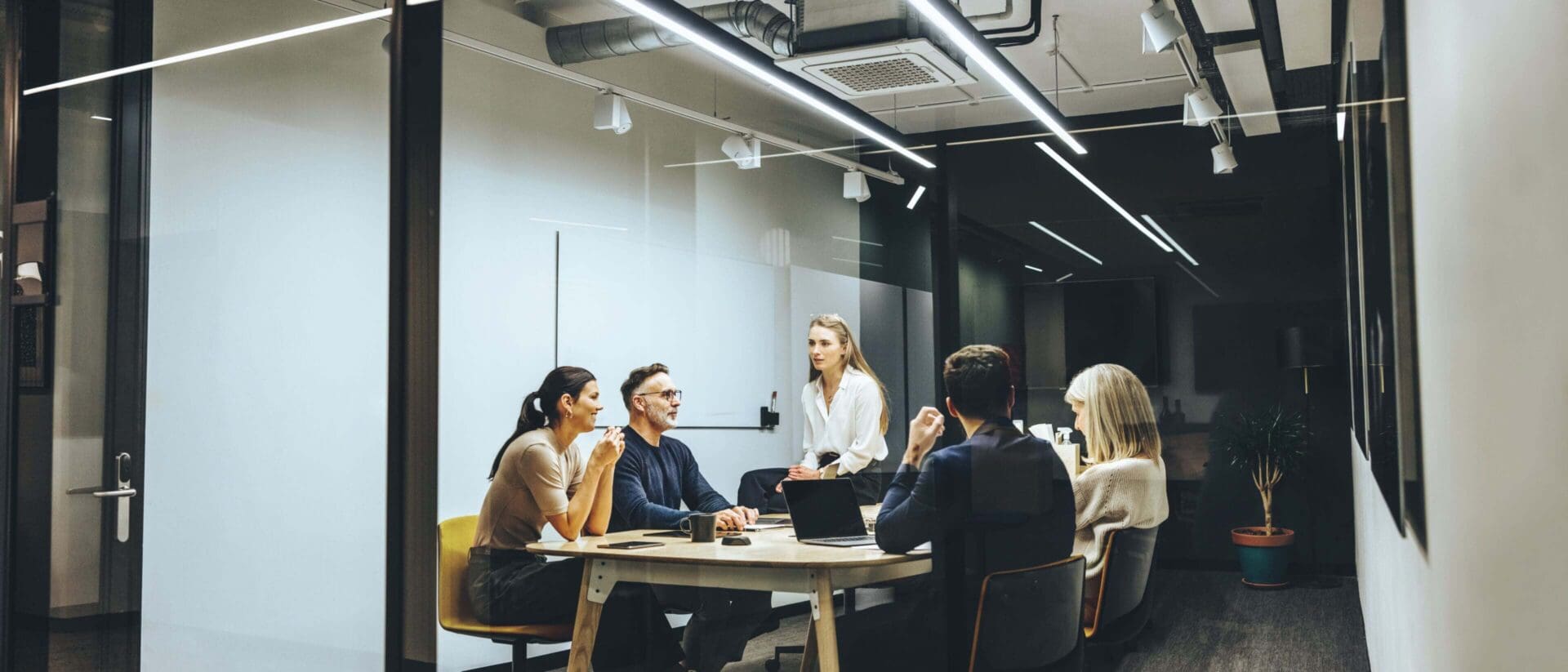 Group of colleagues having a meeting in a transparent boardroom. Team of diverse business professionals having a discussion during a briefing. Businesspeople collaborating on a new project.