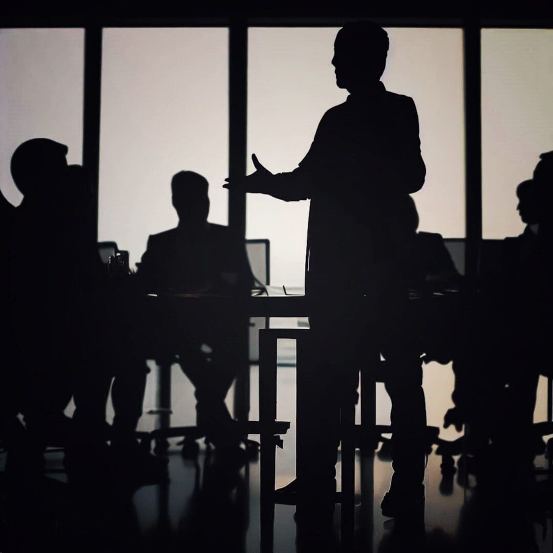 Silhouetted business meeting in dimly lit room.