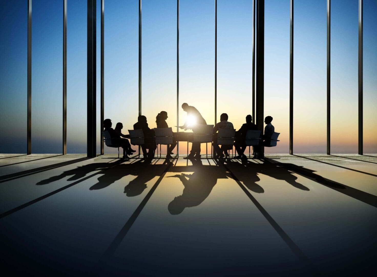 Silhouetted meeting in a sunset-lit room.