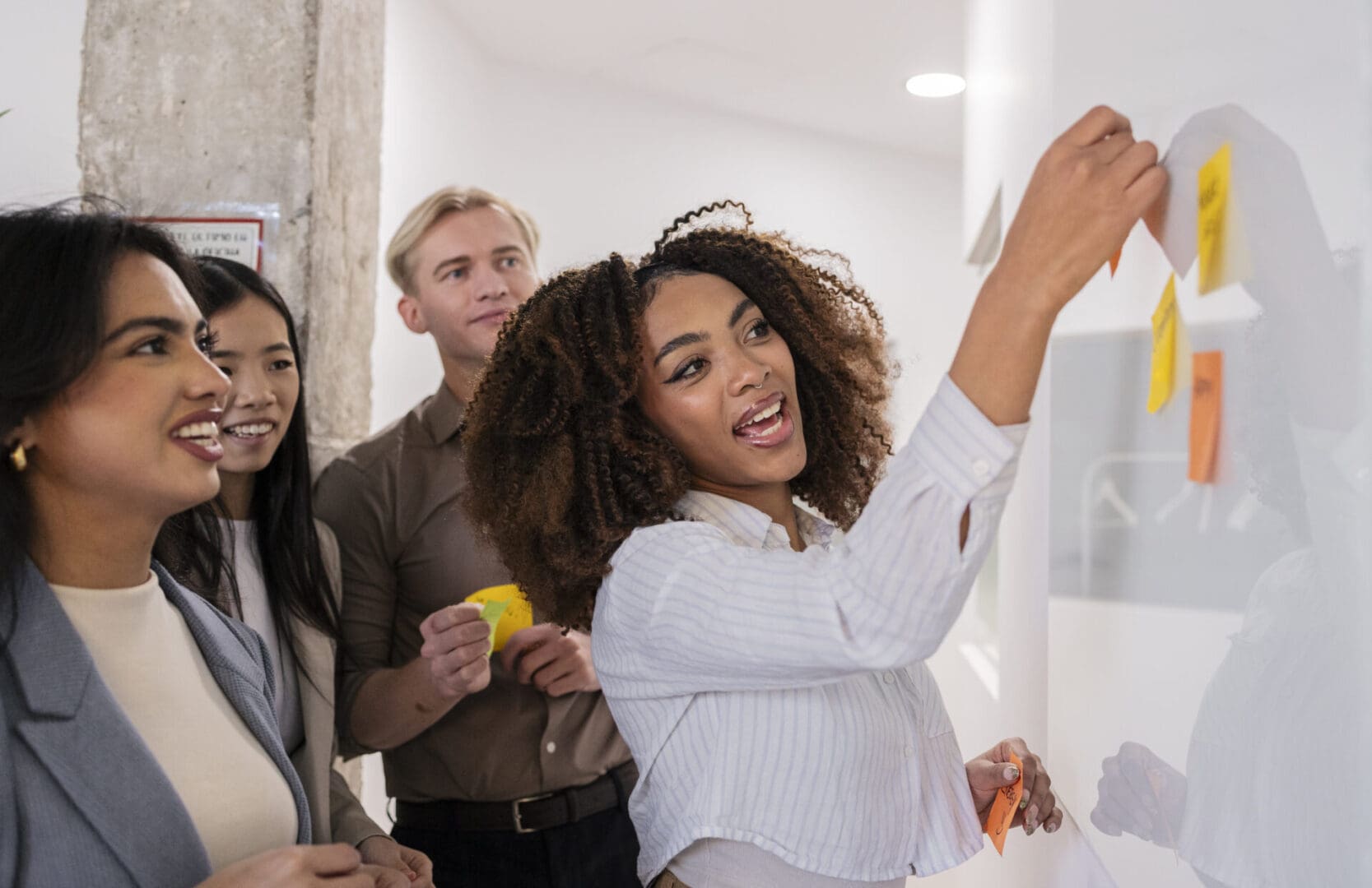 Diverse marketing team collaborating and sharing ideas during a productive brainstorming session, using colorful sticky notes on a whiteboard to visualize and organize their thoughts