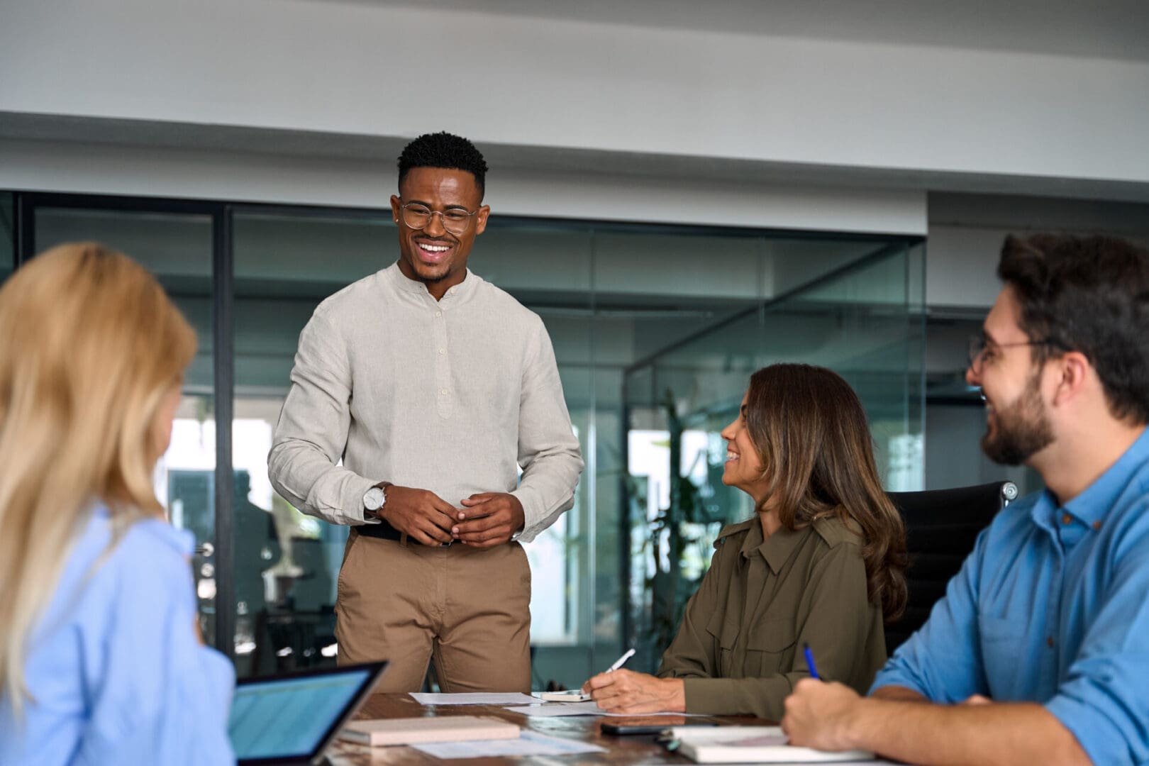 Team leader, young happy African American male executive company manager discussing project management planning strategy working with diverse busy colleagues at office corporate board group meeting.