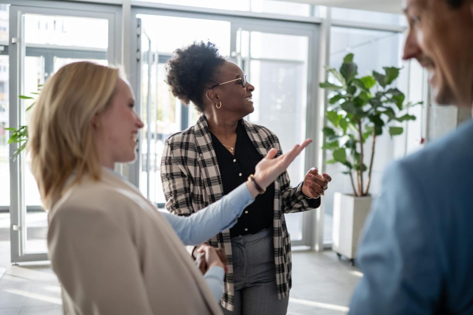Business colleagues networking and discussing ideas, smiling during a casual conversation in a bright modern office setting