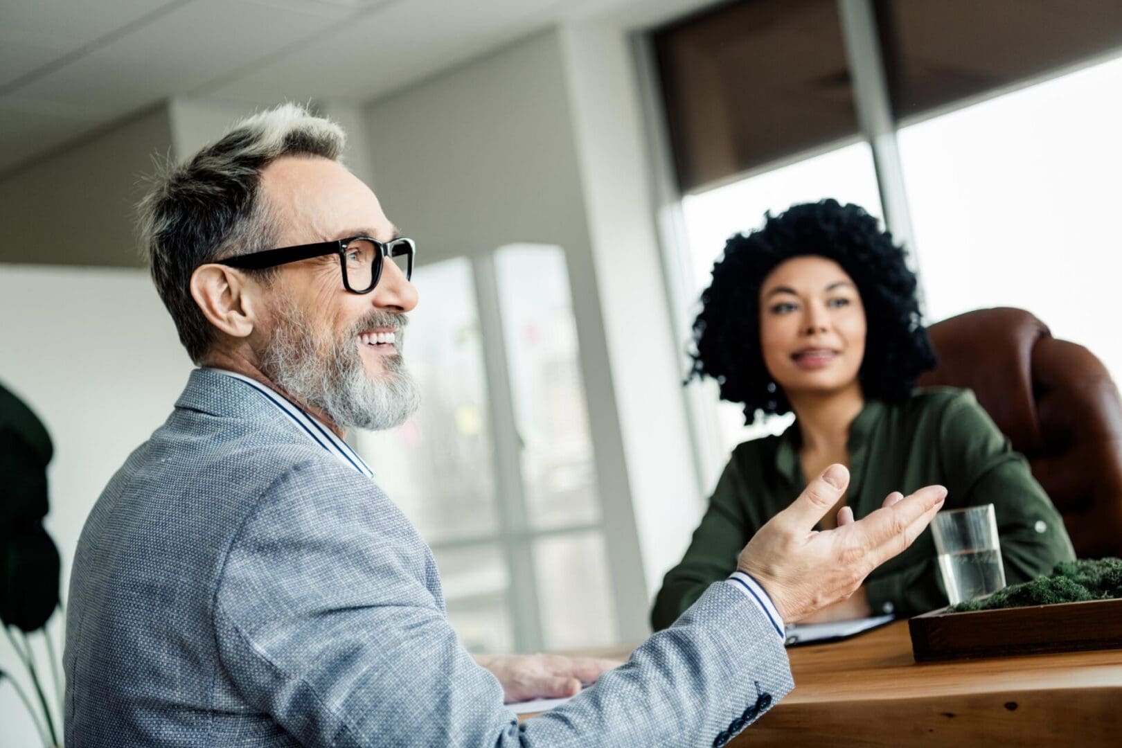 Dynamic business meeting involving a confident man and a woman collaborating in a bright, elegant office space.
