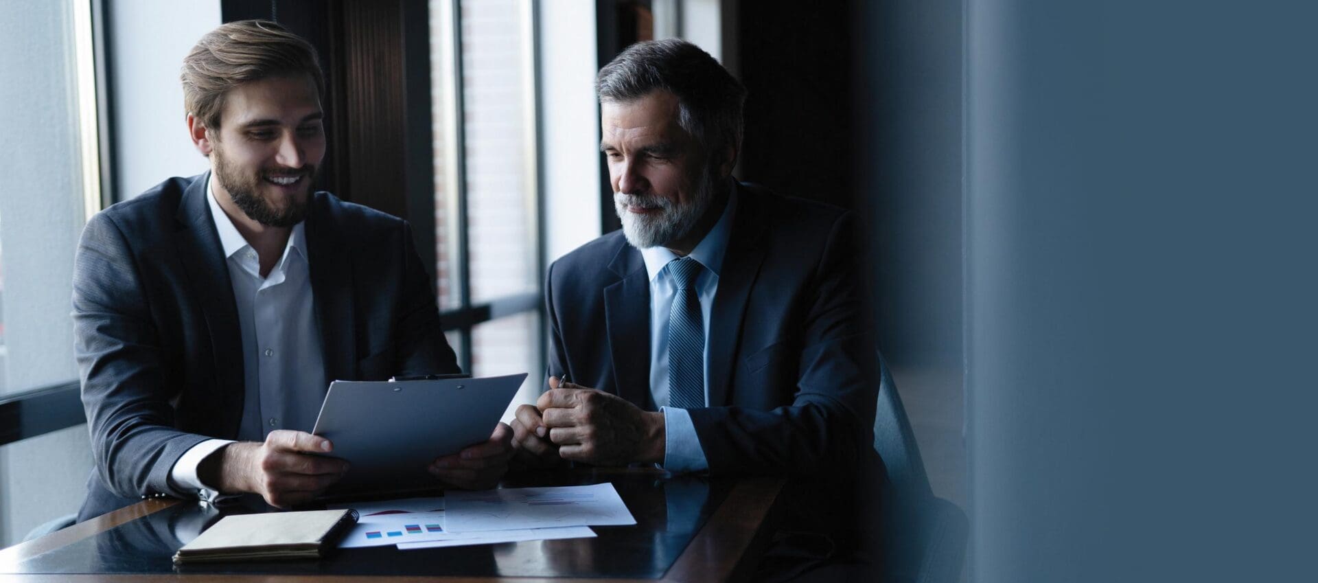 Good deal. Senior and junior businessman discuss something during their meeting, office background