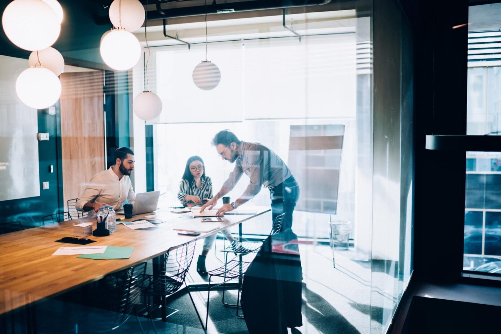 Multiracial business team having meeting in conference room and preparing presentation of business project while working with documents and laptop