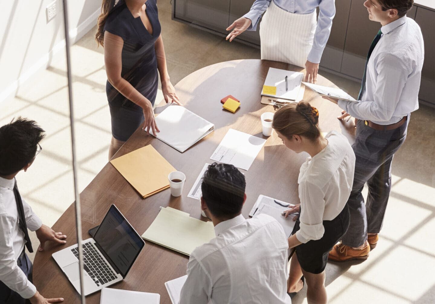 Office meeting with five professionals discussing documents.