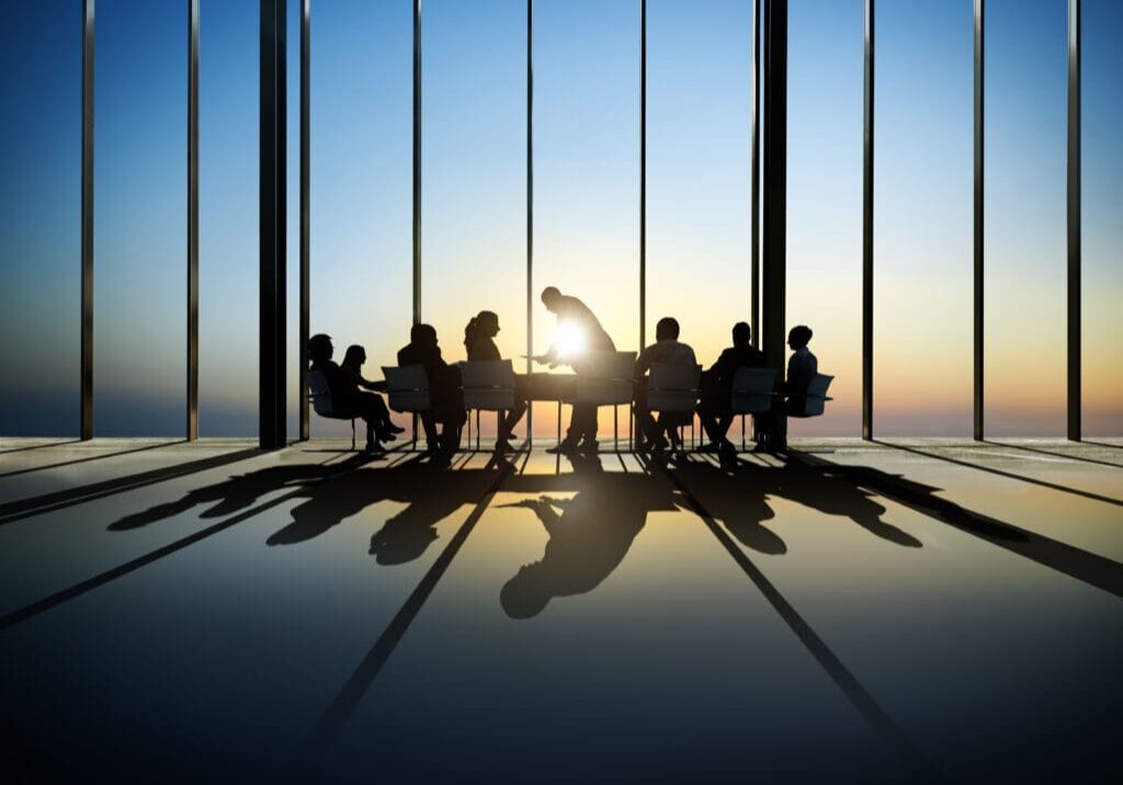 Silhouetted meeting in a sunset-lit room.