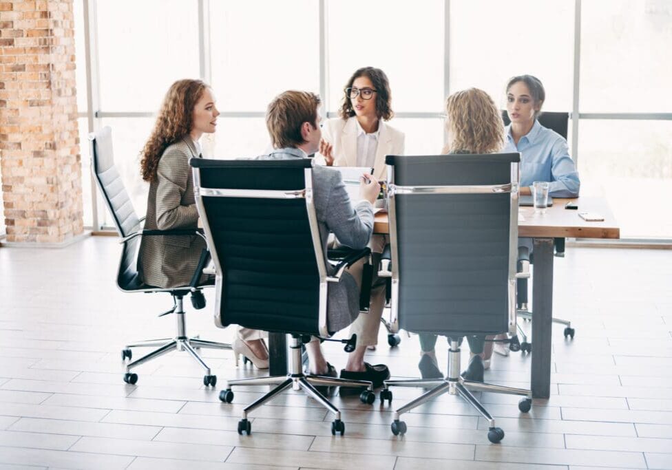 Business meeting with five people at table.