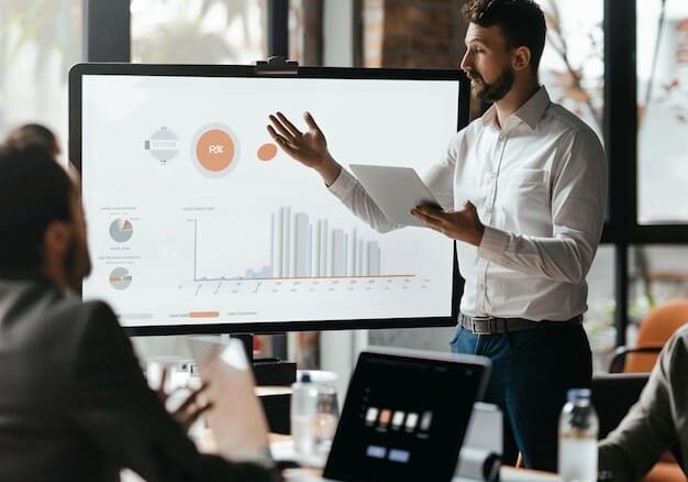 Man presenting data on large screen.