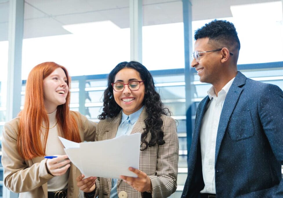 Three colleagues discussing documents at work.