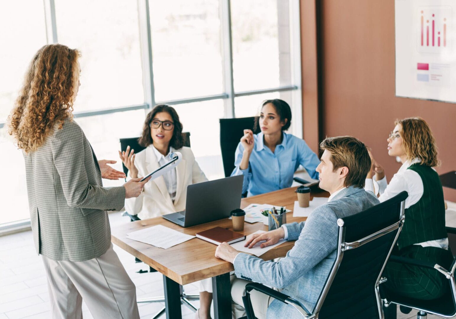 Business professionals in a modern office engaging in a teamwork-focused meeting to discuss strategies and corporate goals. Various roles and collaboration dynamics are illustrated within a workplace environment.