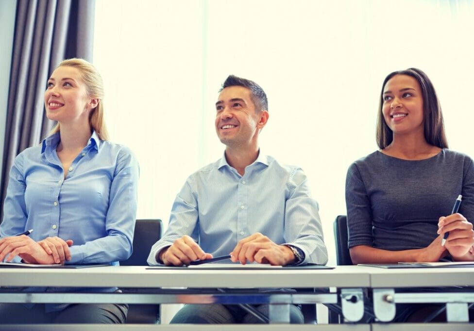 Three people smiling at a meeting.