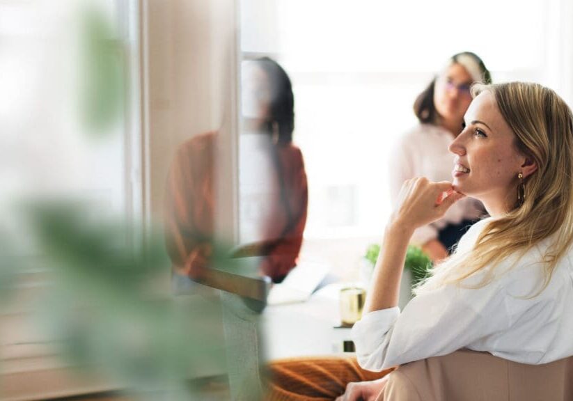 Woman thinking during a meeting, blurred background.
