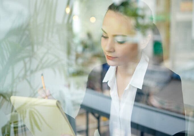 Businesswoman working at desk with reflection.