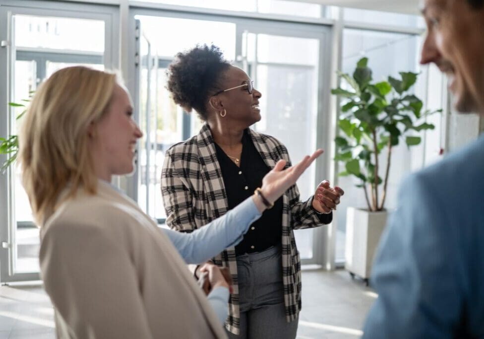 Business colleagues networking and discussing ideas, smiling during a casual conversation in a bright modern office setting