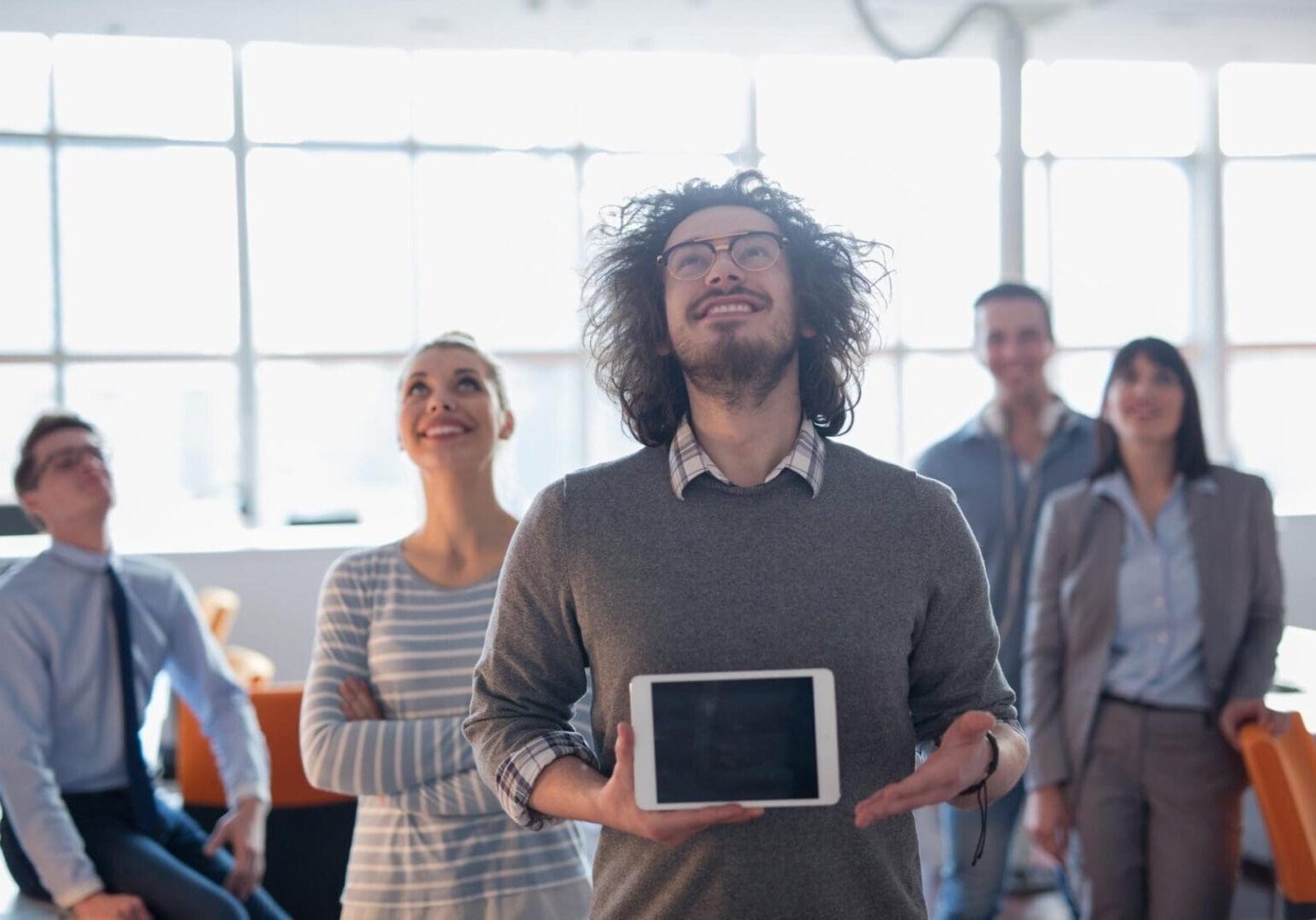 Smiling team looking up, man holding tablet