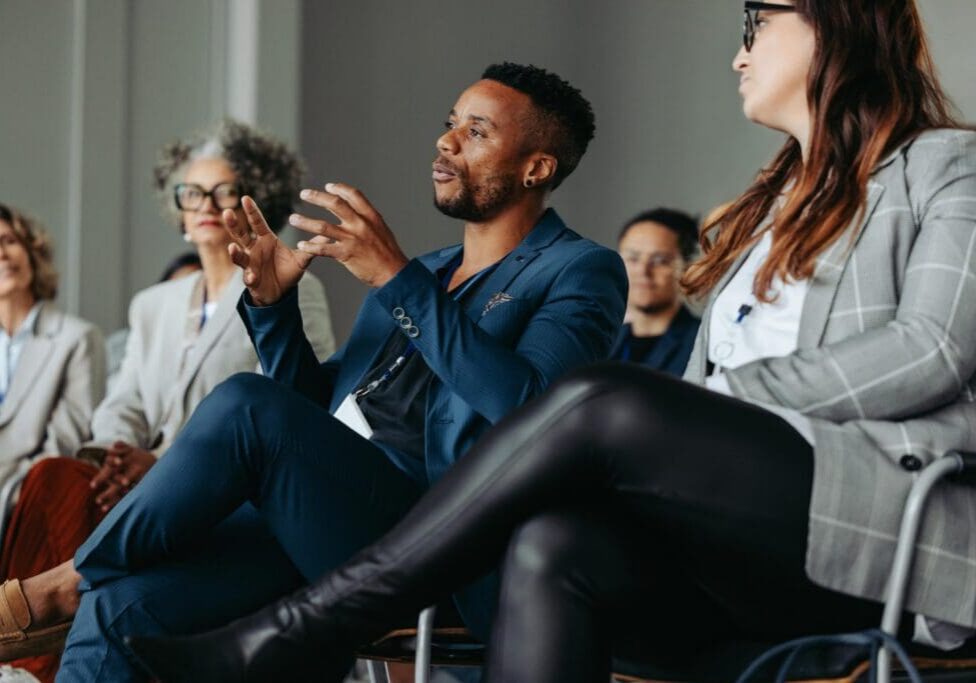 Black business man passionately speaking during a workshop with colleagues in a professional conference setting.