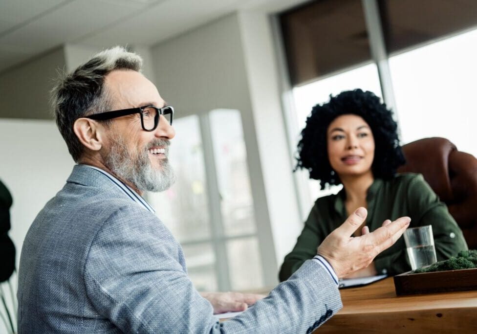 Dynamic business meeting involving a confident man and a woman collaborating in a bright, elegant office space.