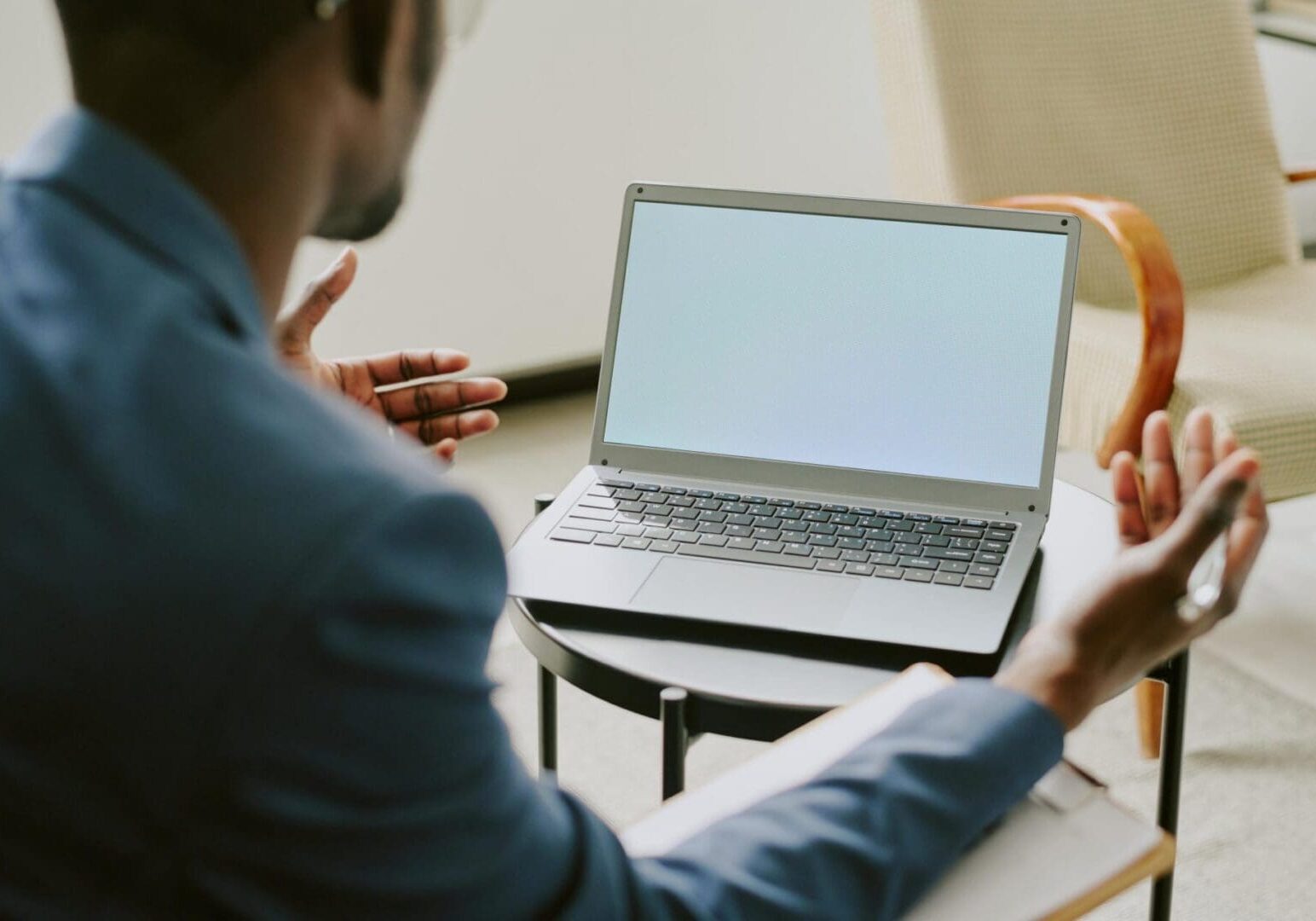 Person gesturing toward laptop with blank screen