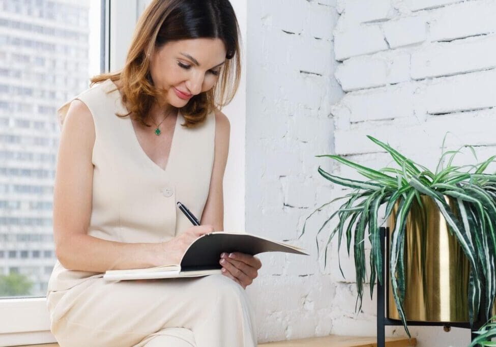 Woman taking notes next to potted plant