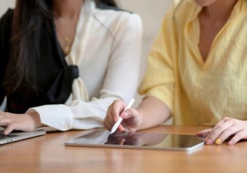 Two people using laptop and tablet