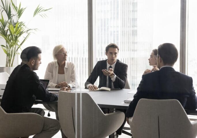 Colleagues discussing strategy in glass-walled office