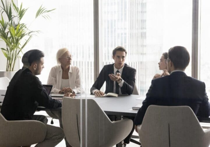 Colleagues discussing strategy in glass-walled office