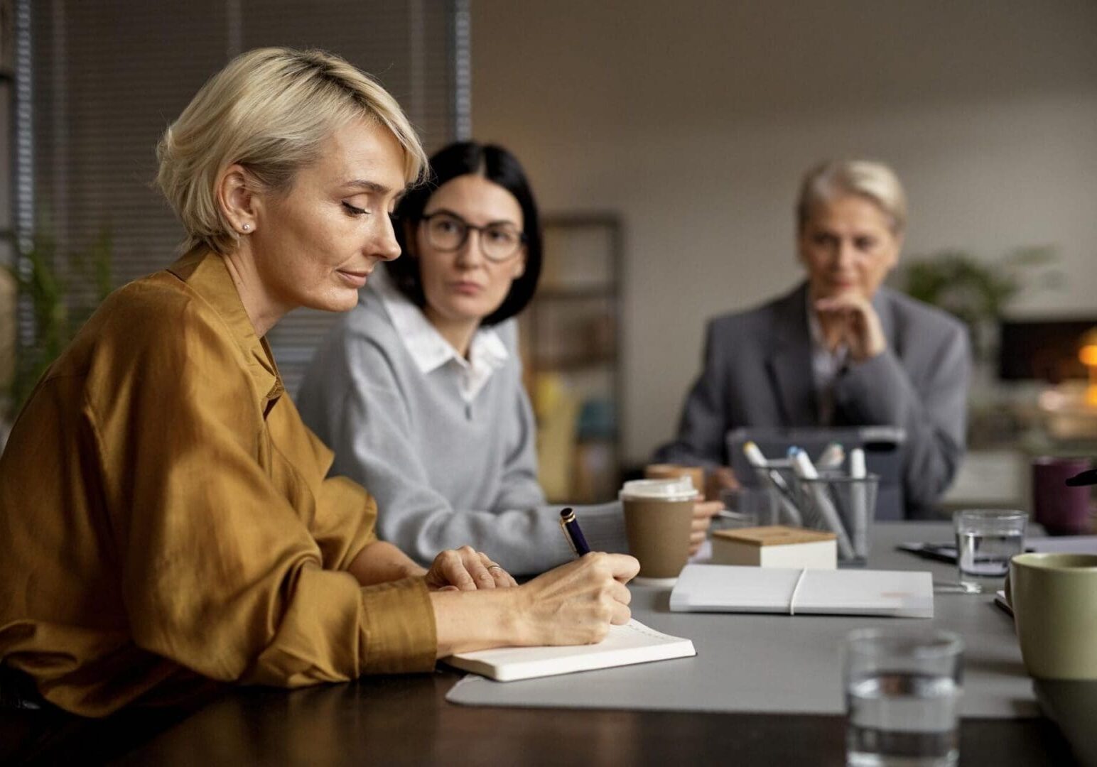 Three women in meeting, one taking notes