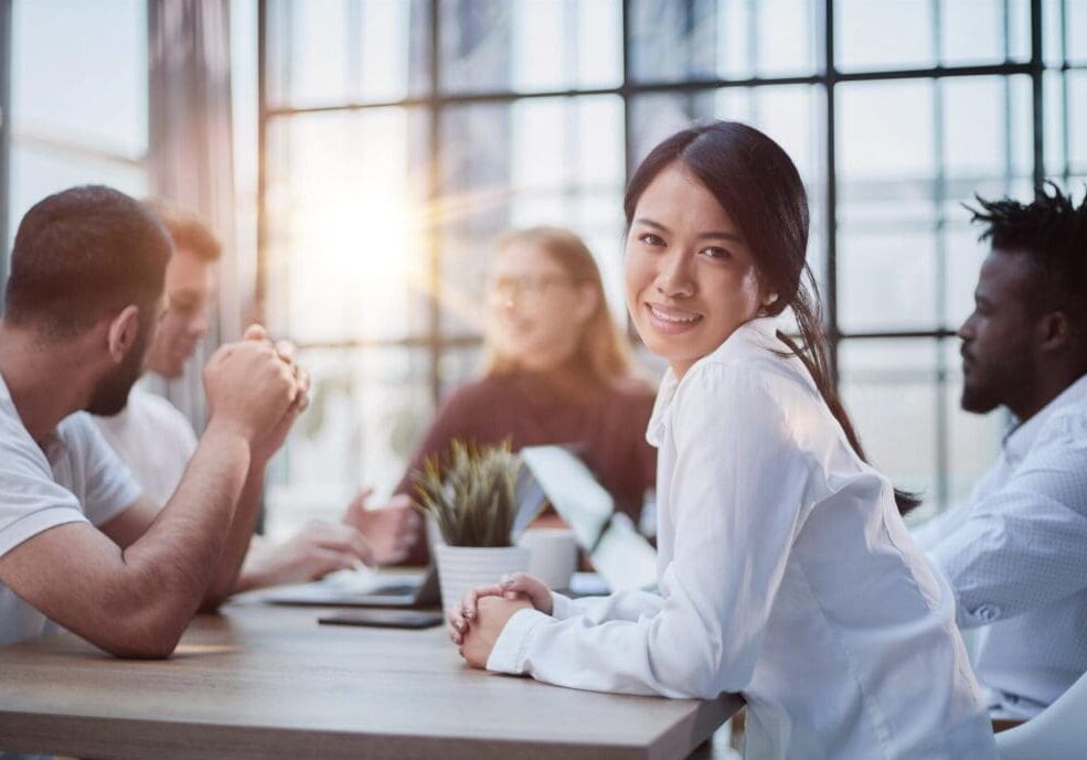 Smiling woman with coworkers in modern meeting