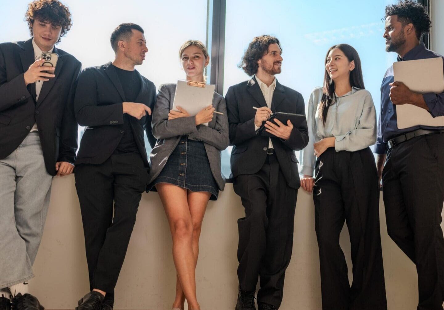 Young professionals chatting by window with clipboards