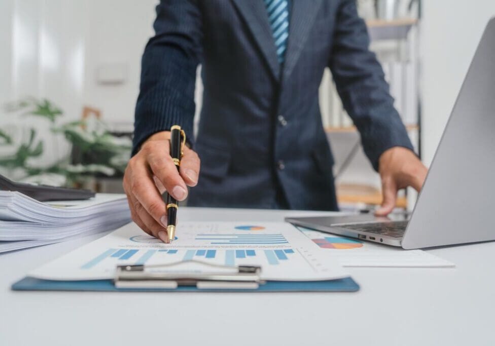 Businessperson pointing at financial charts on desk