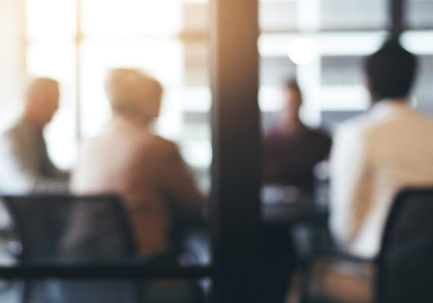 Blurred group meeting in sunny office