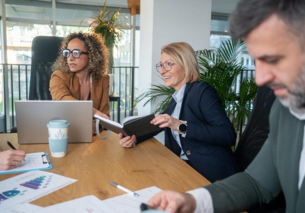 Colleagues collaborating at meeting table with laptop