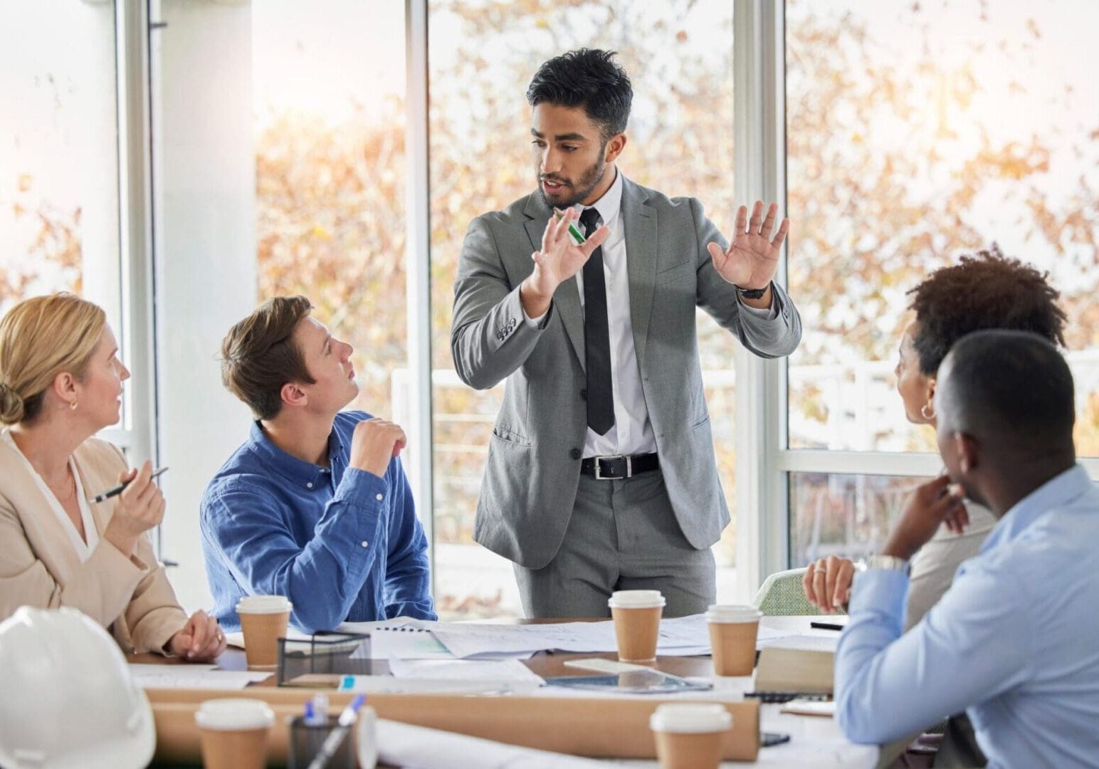 Man in suit presenting to colleagues at meeting