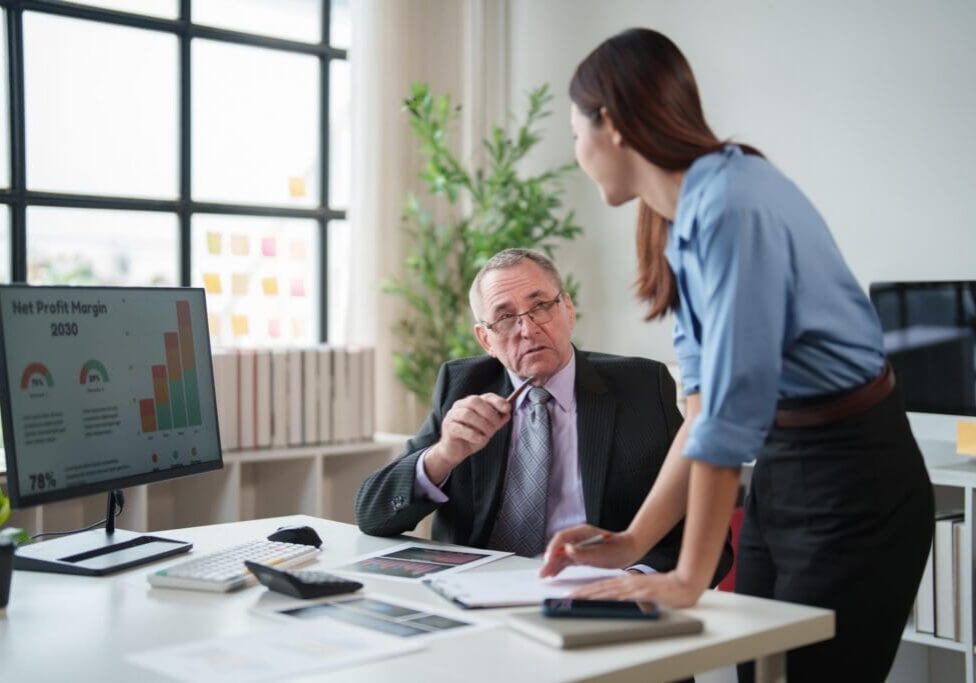 Colleagues reviewing profit charts at office desk