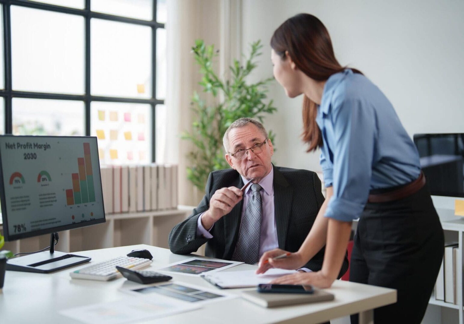 Colleagues reviewing profit charts at office desk