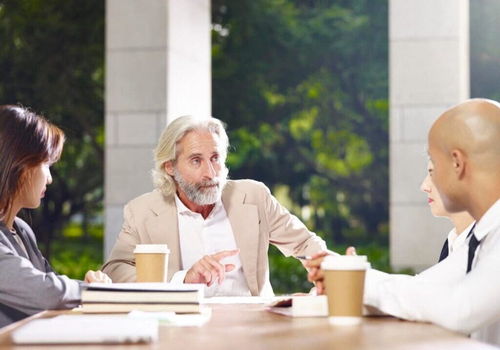 Older man leading outdoor business meeting