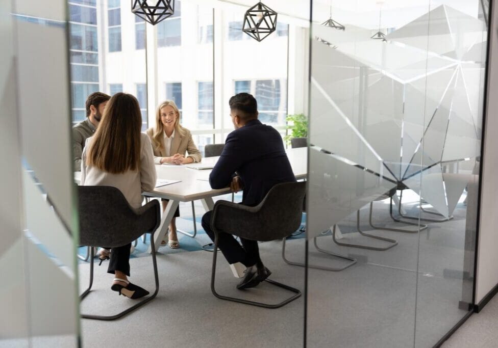 Four colleagues meeting in glass conference room