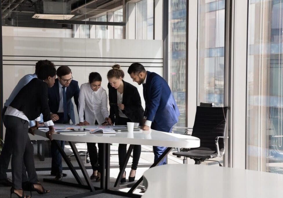 Group of multi ethnic teammates gathered together for project financial stats discussion, do paperwork at meeting briefing, diverse employees brainstorm cooperate in office boardroom, teamwork concept