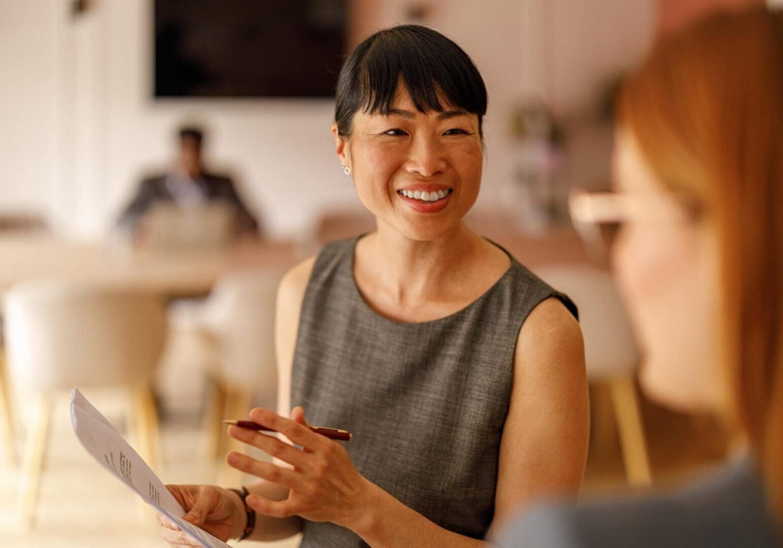 Successful female manager discussing project documents and sharing ideas with coworker in modern workplace