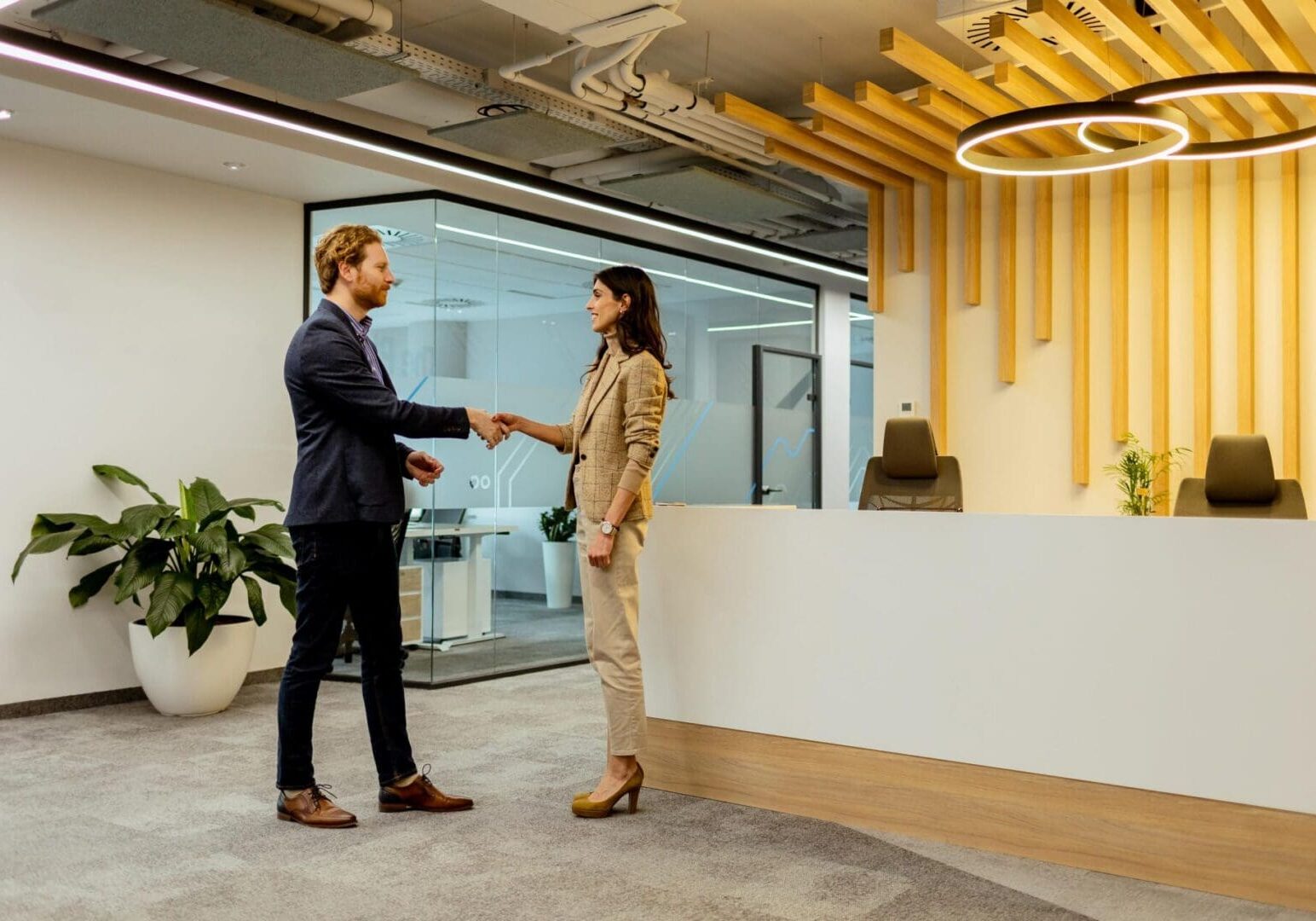 Two professionals exchanging greetings with a friendly handshake in a sleek office environment