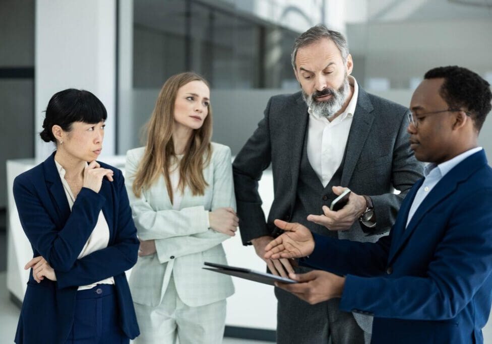 Four diverse business professionals collaborating during a discussion, planning and communicating corporate ideas in a modern office