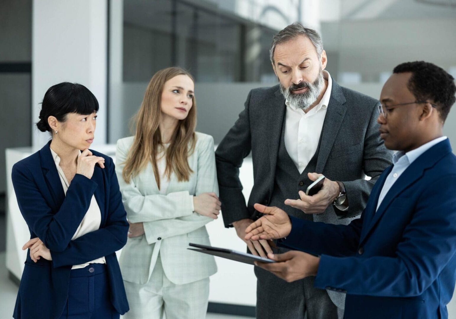 Four diverse business professionals collaborating during a discussion, planning and communicating corporate ideas in a modern office