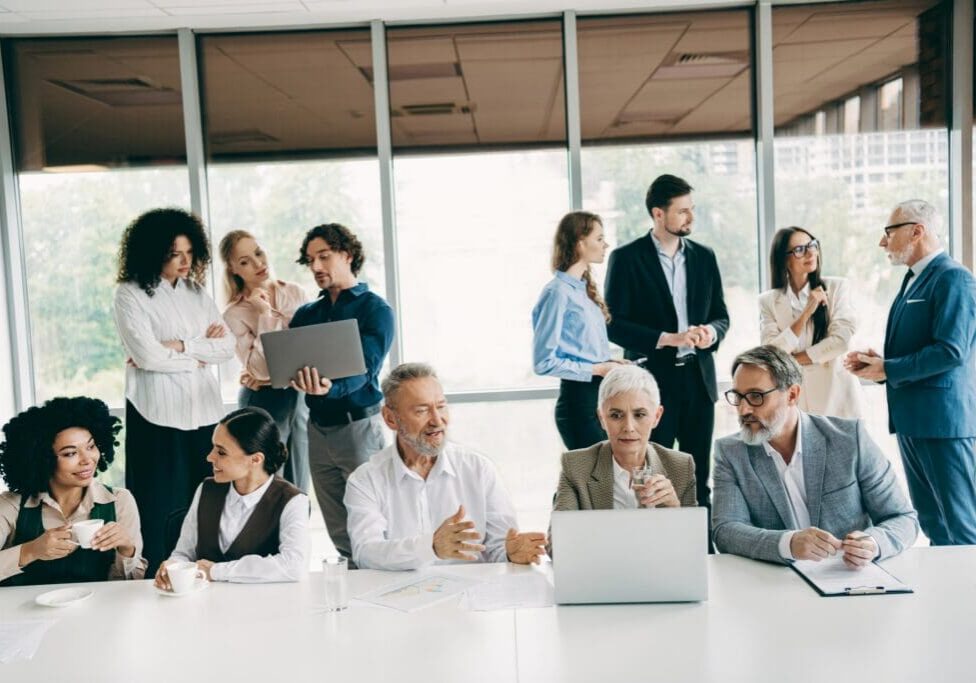 Diverse group of colleagues engaging in teamwork and communication at a bright workspace, fostering collaboration and idea sharing.