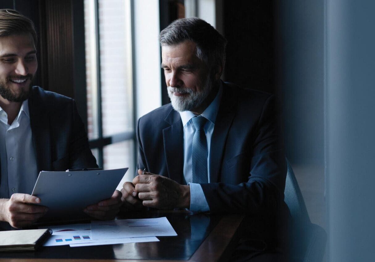 Good deal. Senior and junior businessman discuss something during their meeting, office background
