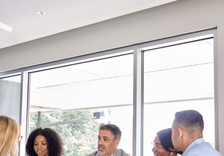 Happy busy international professional executive business team diverse colleagues employees work group talking consulting planning project, having conversation at office corporate meeting. Vertical