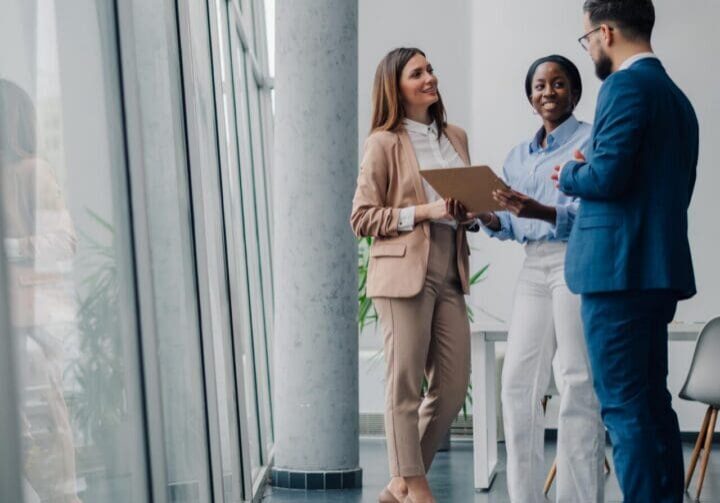 Business colleagues reviewing documents and discussing work in office hallway