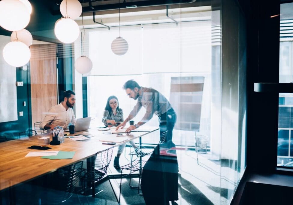 Multiracial business team having meeting in conference room and preparing presentation of business project while working with documents and laptop